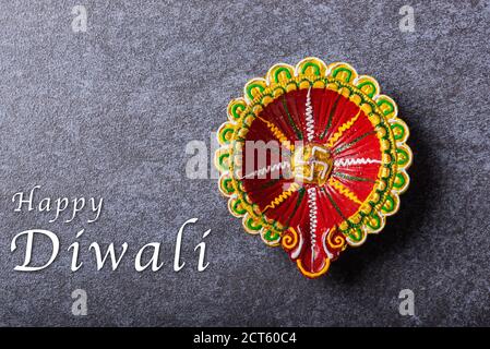 Vista dall'alto lampada Diya o ad olio in argilla illuminata, studio girato su fondo di cemento, decorazione di rangoli induisti, Happy Deepavali o Diwali festival co Foto Stock