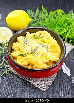 Gnocchi di zucca con salvia, limone, formaggio e burro in una ciotola su tela contro tavola di legno scuro Foto Stock