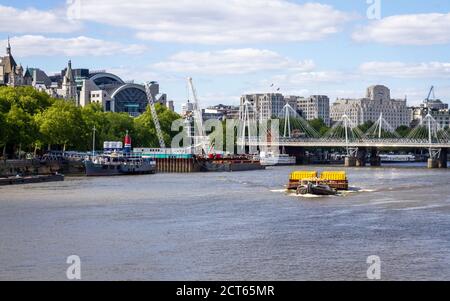 Rimorchiatore barca che tira il trasporto come contenitori in un grande separato Chiatta lungo il Tamigi a Londra Foto Stock