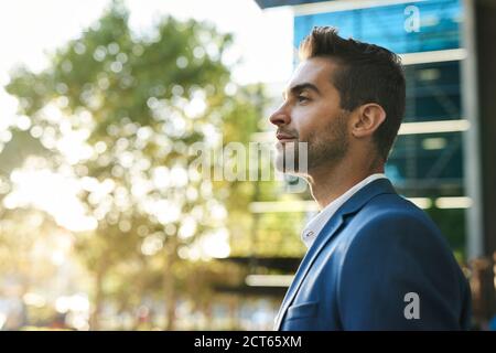 Giovane uomo d'affari che cammina in città in un pomeriggio di sole Foto Stock