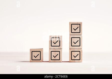 Segno di spunta sui blocchi di legno su sfondo blu con spazio per la copia. Concetto di lista di controllo. Foto Stock