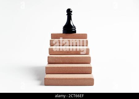 Pawn in cima alle scale fatto con blocchi di legno su sfondo bianco. Carriera, successo o promozione nel concetto di business. Foto Stock