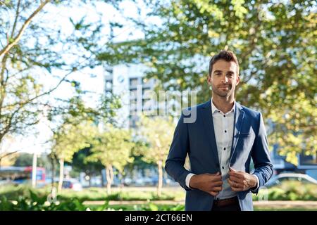 Elegante giovane uomo d'affari che si erge da solo fuori dalla città Foto Stock