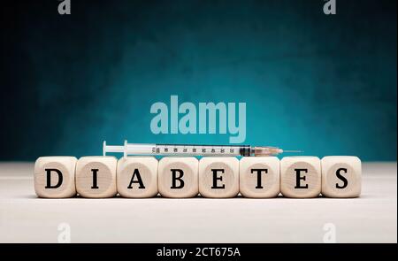 La parola diabete su cubi di legno con una siringa di insulina. Concetto di trattamento del diabete e dell'insulina. Foto Stock