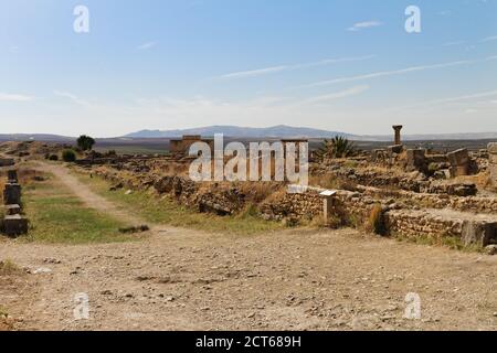 Vista di Volubilis, patrimonio mondiale dell'UNESCO in Marocco, scavato vecchia città berbera vicino alla città di Meknes. Arco trionfale, campi agricoli e. Foto Stock