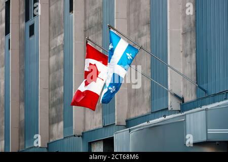 Bandiere del Quebec e del Canada che battono su un edificio nel centro di Montreal. Foto Stock