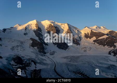 Die ebenfalls dreigipflige Palü und die ebenfalls dreigipflige Bellavista (von links). Davor der Persgletscher. Bei Sonnenaufgang. Oberengadin, Kanton Graub Foto Stock