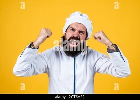 aspetto poco amichevole. gridare l'uomo arrabbiato. concetto di pulizia. uomo maturo indossare cappello chef. cuoco maschio pronto per preparare il cibo. hipster brutale in grembiule che sta cucinando pasto. tempo di mangiare. Foto Stock