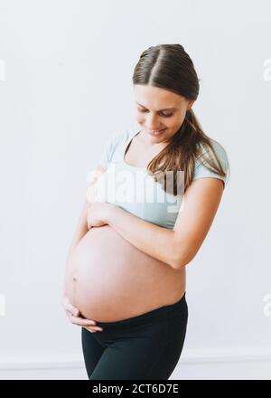 Giovane donna incinta sorridente nello sport che indossa isolato sul sfondo bianco Foto Stock