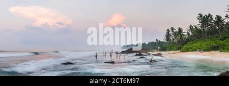 Stilt pescatori a sunrise a Midigama Beach, vicino Weligama, South Coast, Sri Lanka, Asia Foto Stock
