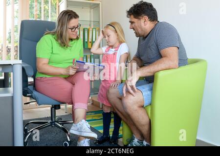 Padre e figlia preschooler in ufficio terapeuta durante la riunione di valutazione di consulenza. Assistente sociale che parla con singolo padre durante l'intervista. Foto Stock