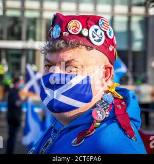 Scozzese sostenitore dell'indipendenza con una maschera di salvataggio una berrata di glengarry con badge pro indipendenza, presa ad un raduno politico di indipendenza, Foto Stock