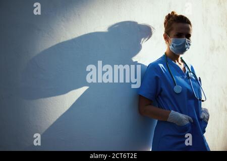 coronavirus pandemic. stanco donna medico moderna in uniforme con stetoscopio, maschera medica e guanti di gomma all'aperto nella città vicino wa Foto Stock