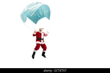 Babbo Natale che vola su un'enorme maschera facciale come su un pallone isolato su sfondo bianco. Modello maschio caucasico in costume tradizionale. Capodanno, regali, vacanze, inverno, COVID, concetto pandemico. CopySpace. Foto Stock