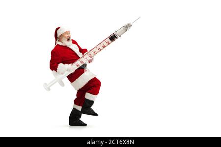 Babbo Natale che contiene vaccino enorme contro COVID come regalo di Natale isolato su sfondo bianco. Modello maschile in costume tradizionale. Capodanno, vacanze, inverno, epidemia, pandemia concetto. CopySpace. Foto Stock