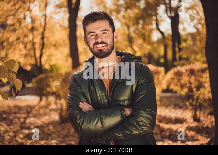 Ritratto di attraente positivo ragazzo croce mani in autunno parco fuori dal centro città Foto Stock