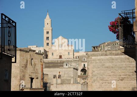 Vista panoramica sulla città del duomo di Matera in collina e case di pietra intorno con cielo blu chiaro sopra e. due ringhiere in ferro nero in primo piano Foto Stock