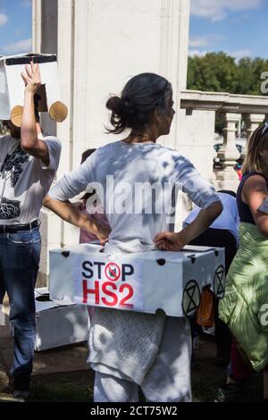 St. James'Park, Londra, Regno Unito. Una donna si guarda intorno come STOP HS2 manifestanti vestito come un treno umano da eseguire per le strade Foto Stock