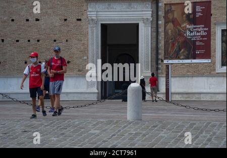 due ragazzi vestiti con t-shirt rosse passeggiano di fronte Il Palazzo Ducale Foto Stock