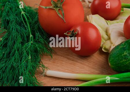 Un set di verdure composto da pomodori, cetrioli, prezzemolo, aneto e cavolo. Su un tagliere Foto Stock