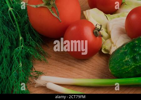 Un set di verdure composto da pomodori, cetrioli, prezzemolo, aneto e cavolo. Su un tagliere Foto Stock