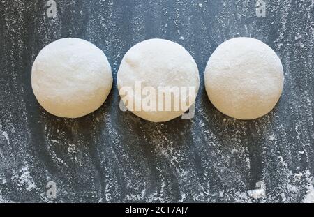 Tre palle di pasta fresca fatta in casa sul tavolo da cucina. Cottura a casa. Impasto per la cottura della pizza, gnocchi di pasta o bread.Horizontal. Foto Stock