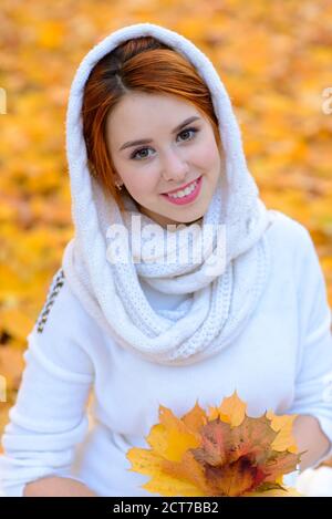 Carina ragazza in lungo vestito bianco di nozze che posa in un percorso rurale tra alberi autunnali nella foresta in atmosfera d'ora d'oro. Foto Stock