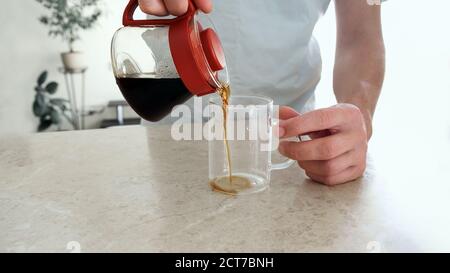 L'uomo versa un caffè appena preparato in una tazza di vetro dal server di vetro. Pourover, V60. Foto Stock