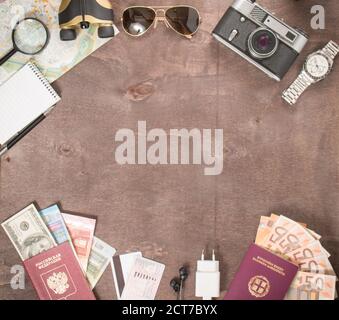 Vista dall'alto di accessori, passaporti e banconote del viaggiatore. Concetto di viaggio su sfondo di legno. Preparazione e pianificazione delle vacanze. Foto Stock