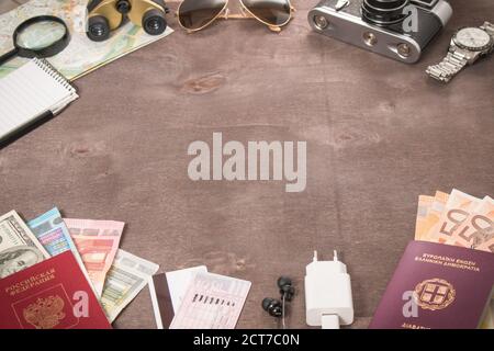 Vista dall'alto di accessori, passaporti e banconote del viaggiatore. Concetto di viaggio su sfondo di legno. Preparazione e pianificazione delle vacanze. Foto Stock