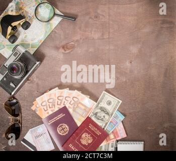 Vista dall'alto di accessori, passaporti e banconote del viaggiatore. Concetto di viaggio su sfondo di legno. Preparazione e pianificazione delle vacanze. Foto Stock