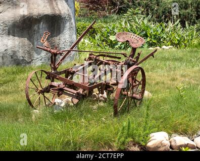 Vecchio aratro arrugginito su un prato verde Foto Stock