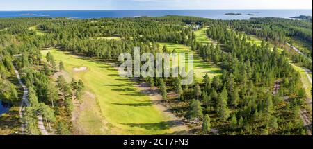 Panorama aereo su pochi campi da golf stretti e lunghi nella foresta settentrionale. I golfisti non identificati giocano a golf sul campo da golf, alberi di pino intorno, Mar Baltico su ho Foto Stock