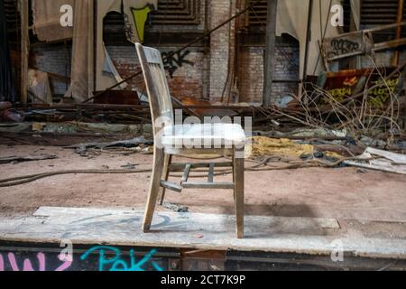 Una sedia di legno vecchia e rotta sul palco di Un Teatro abbandonato Foto Stock