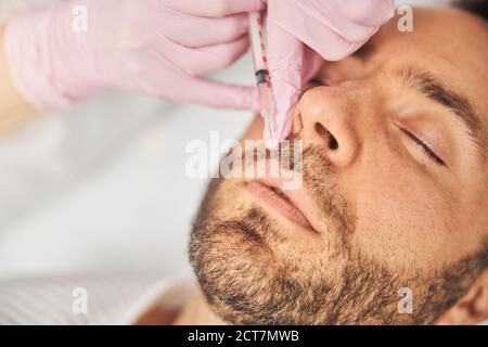Giovane uomo non rasato che riceve iniezione cosmetica presso il centro benessere Foto Stock