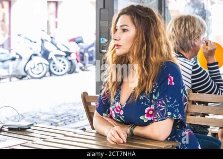 La ragazza siede nell'affascinante caffetteria sulla collina di Montmartre. Montmartre, con i tradizionali caffè francesi e le gallerie d'arte, è uno dei punti di riferimento più visitati Foto Stock