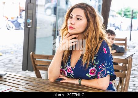 La ragazza siede nell'affascinante caffetteria sulla collina di Montmartre. Montmartre, con i tradizionali caffè francesi e le gallerie d'arte, è uno dei punti di riferimento più visitati Foto Stock