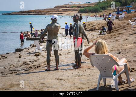 Turisti che applicano il fango del Mar Morto che possiede le qualità medicinali e aiuta le persone con problemi di pelle. Trattamento di cura del corpo in Israele. Morto Foto Stock