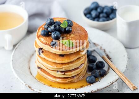 Pancake con mirtilli e miele su un piatto. Colazione frittelle impilate con frutti di bosco Foto Stock