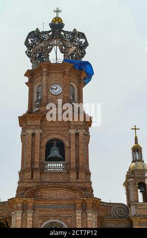 Puerto Vallarta, Messico - 25 aprile 2008: Chiesa di nostra Signora di Guadalupe . Closeup della cima della torre dell'orologio in pietra di mattoni marrone-rosso contro il cielo azzurro Foto Stock