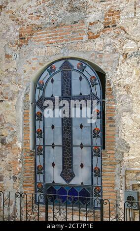 Puerto Vallarta, Messico - 25 aprile 2008: Chiesa di nostra Signora di Guadalupe. Vetrata con croce grigio scuro e fiori rossi all'esterno Foto Stock