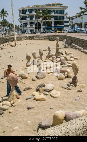 Puerto Vallarta, Messico - 25 aprile 2008: Passeggiata lungo l'oceano a Malecon. Spiaggia sabbiosa dove sono state costruite diverse torri di bilanciamento della roccia e un uomo è l'autobus Foto Stock