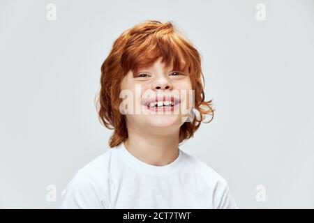 ragazzo rosso viso primo piano sorriso tagliato vista bianca t-shirt grigio sfondo Foto Stock