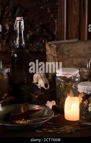 cucina delle streghe con molti ingredienti per una pozione E antiche giare raccapriccianti scuro con solo candele per Halloween Foto Stock