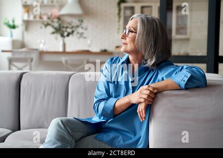 Calma rilassata donna anziana matura rilassante seduta sul divano a casa. Foto Stock