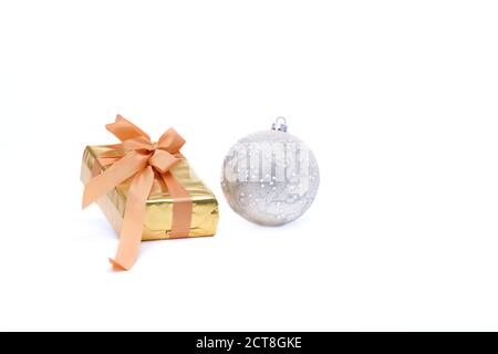 Primo piano di un bel Natale bauble accanto a una confezione regalo in oro su uno sfondo chiaro. Regali di Natale e decorazione concetto. Foto Stock