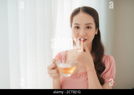 Belle Donne asiatiche mangiare nutrizionali dell'olio di pesce supplemento per la dieta sana a casa Foto Stock