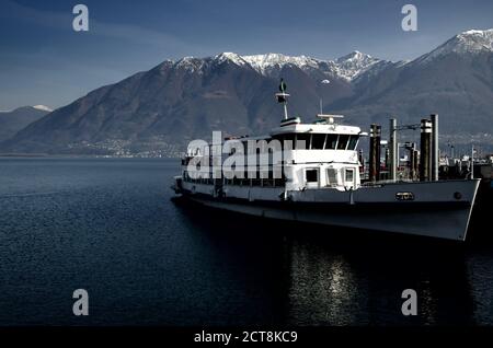 Nave passeggeri sul Lago Alpino maggiore con montagna innevata in Ticino, Svizzera. Foto Stock