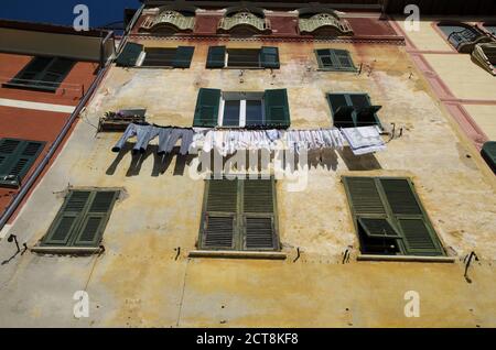 Abiti da essiccazione sulla linea di Wasging all'esterno su un vecchio edificio in Liguria, Italia. Foto Stock