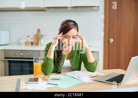 Una giovane casalinga attraente prende in considerazione sgraziatamente spendere questo mese ed è sotto sforzo quando controlla i conti. Foto Stock